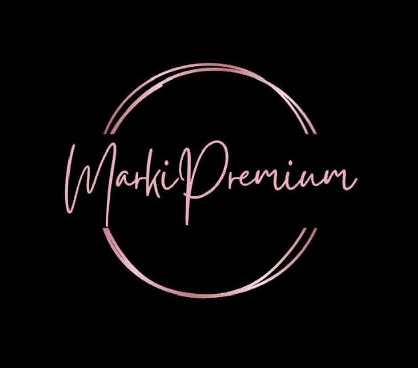 Logo w eleganckim stylu. Na czarnym tle znajduje się fraza "Marki Premium" napisana odręcznym, kursywnym stylem czcionki, otoczona dwoma nieregularnymi, cienkimi okręgami. Cały napis i okręgi są w kolorze różowego złota lub pudrowego różu.