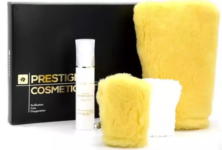 Zestaw Prestige Cosmetics Colway, składający się z czarnego pudełka z logo i białej butelki z pompką z produktem "Intense Moisturizing Serum" oraz dwóch żółtych i jednej białej rękawicy do mycia, prawdopodobnie do ciała.